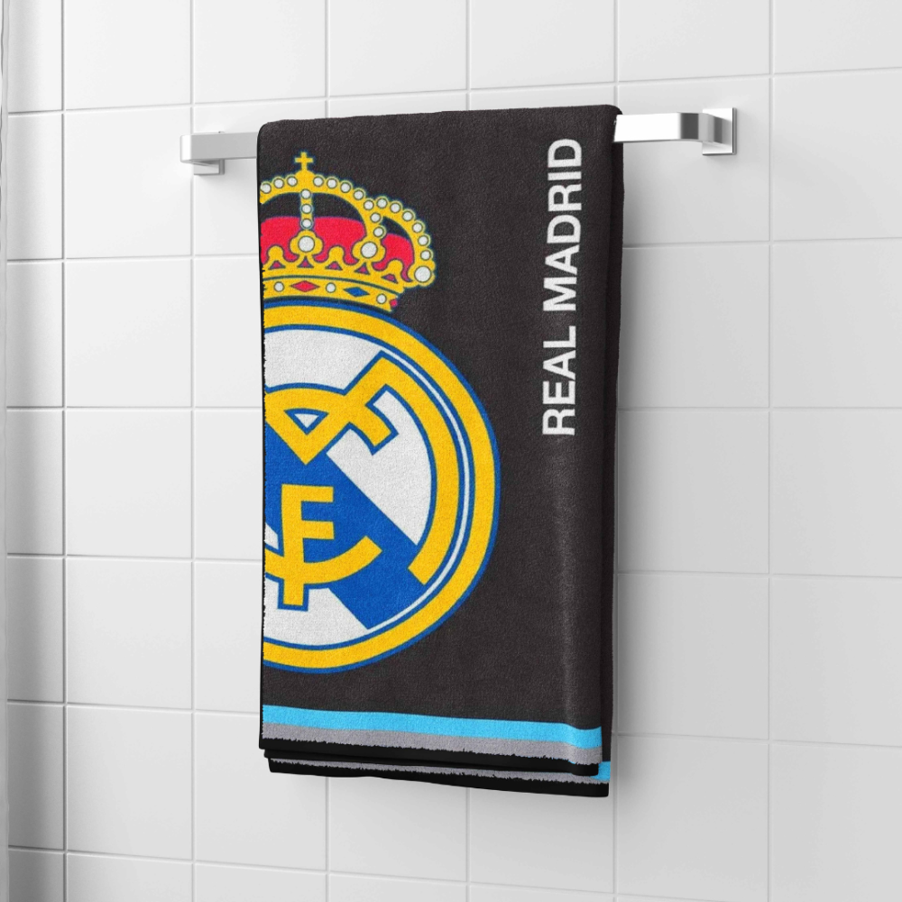 Badetuch „Real Madrid black towel“. Badetücher, 70x140 cm. Schwarzes handtuch mit fußballverein „real madrid“-motiv, aufgehängt im badezimmer, das vereinslogo und der schriftzug sind deutlich sichtbar.